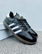Zapatillas Adidas Samba de moda en color negro con detalles blancos, marca Tula, vista frontal y detalles de diseño.