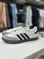 Zapatillas Adidas Samba de moda en color negro con detalles blancos, marca Tula, vista frontal en primer plano.