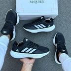 Zapatillas Adidas Ultra Boost de moda en color negro, vistas desde el lateral, con detalles en blanco y suela blanca.