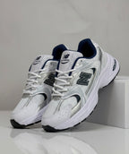 Ropa deportiva Valkyrie New Balance 530 en color gris, vista frontal con detalles de diseño y logotipo en el pecho.