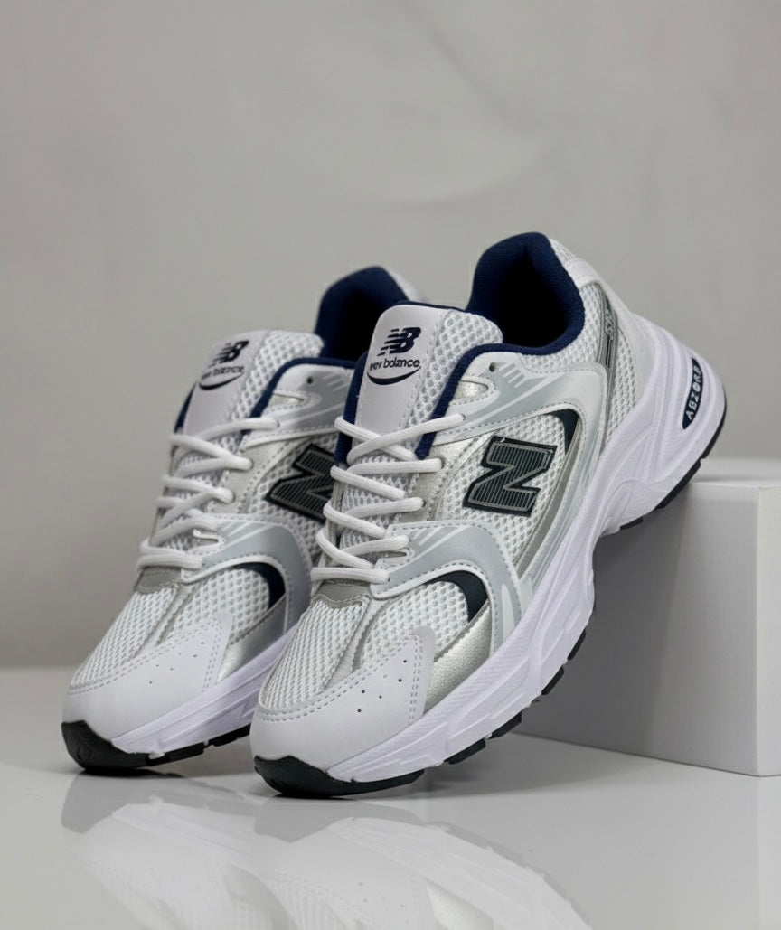 Ropa deportiva Valkyrie New Balance 530 en color gris, vista frontal con detalles de diseño y logotipo en el pecho.