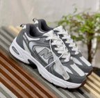 Ropa deportiva Valkyrie para mujer, estilo New Balance 530, en color gris y negro, con detalles de tela transpirable.